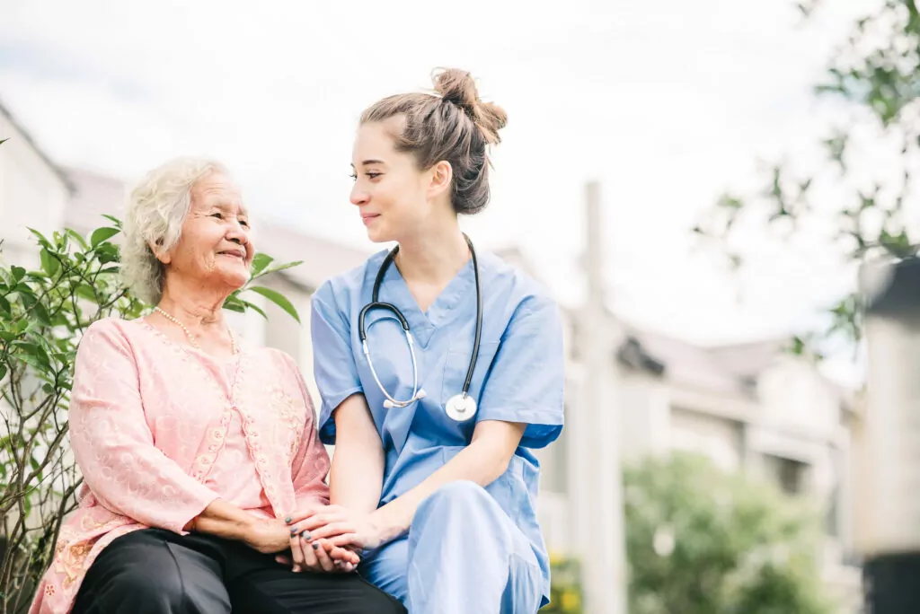 A female Community Care TASMANIA carer sitting with an older woman outside