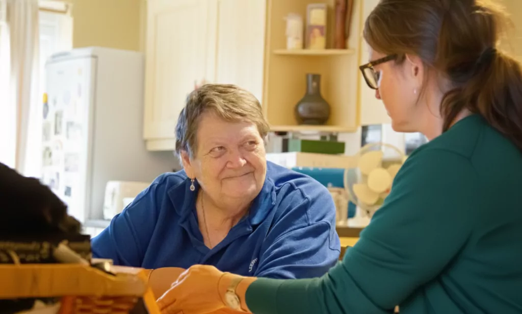 An older woman sitting at her kitchen table while looking at a younger woman