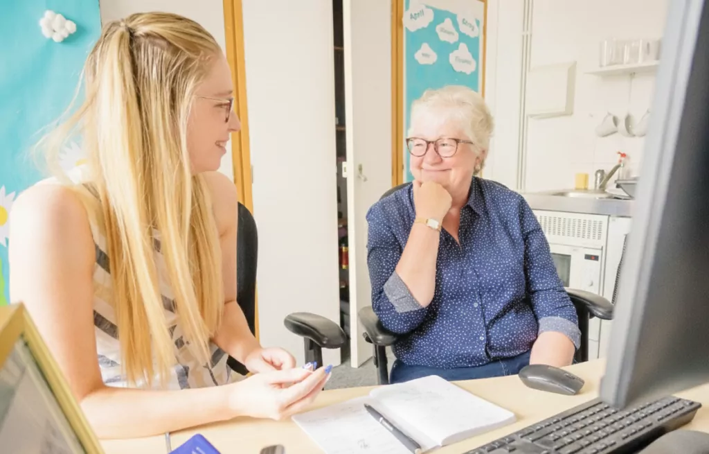 A doctor and her older female patient smiling at each other