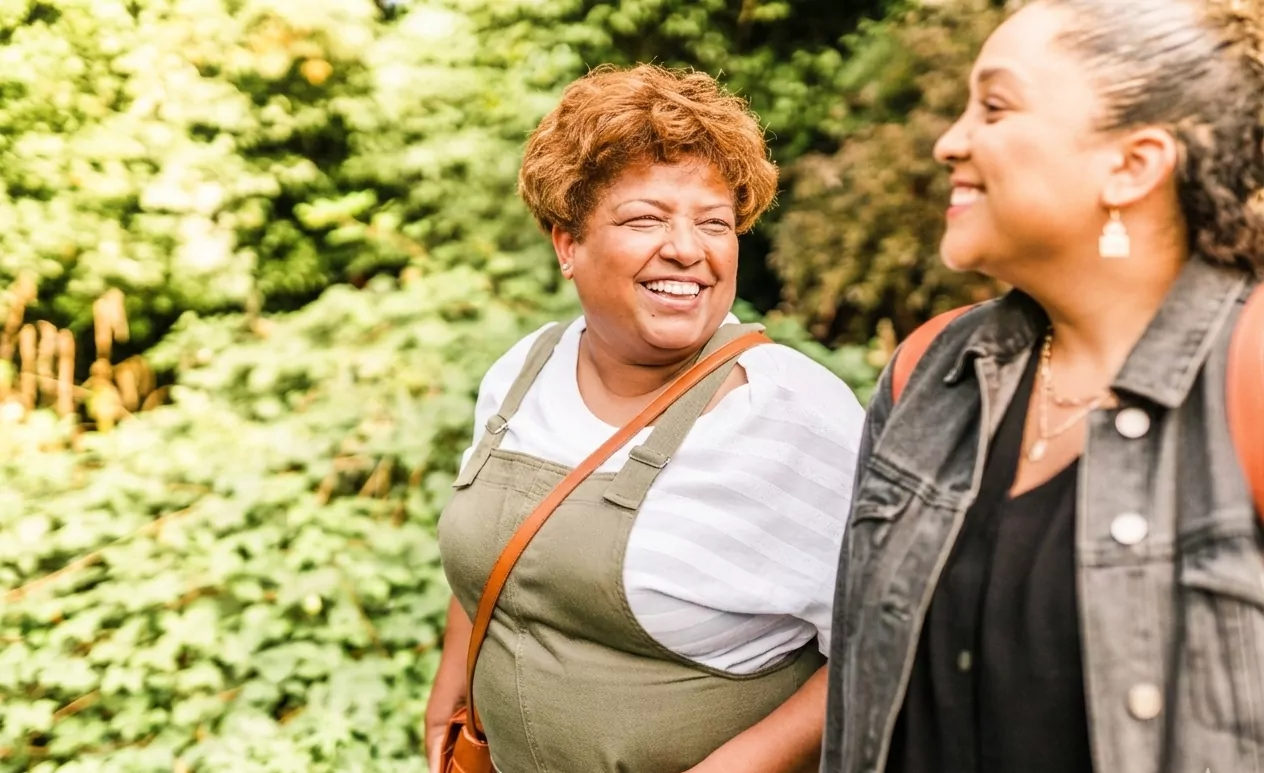 Two older women smiling at each other while going for a walk outside