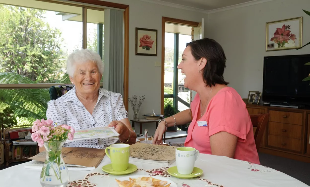 A Community Care TASMANIA worker laughing with an older woman at her kitchen table