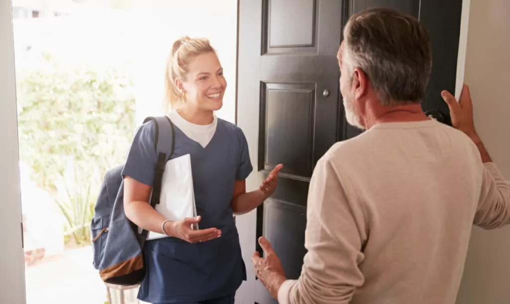 A female nurse from Community Care TASMANIA greeting an older man at the door