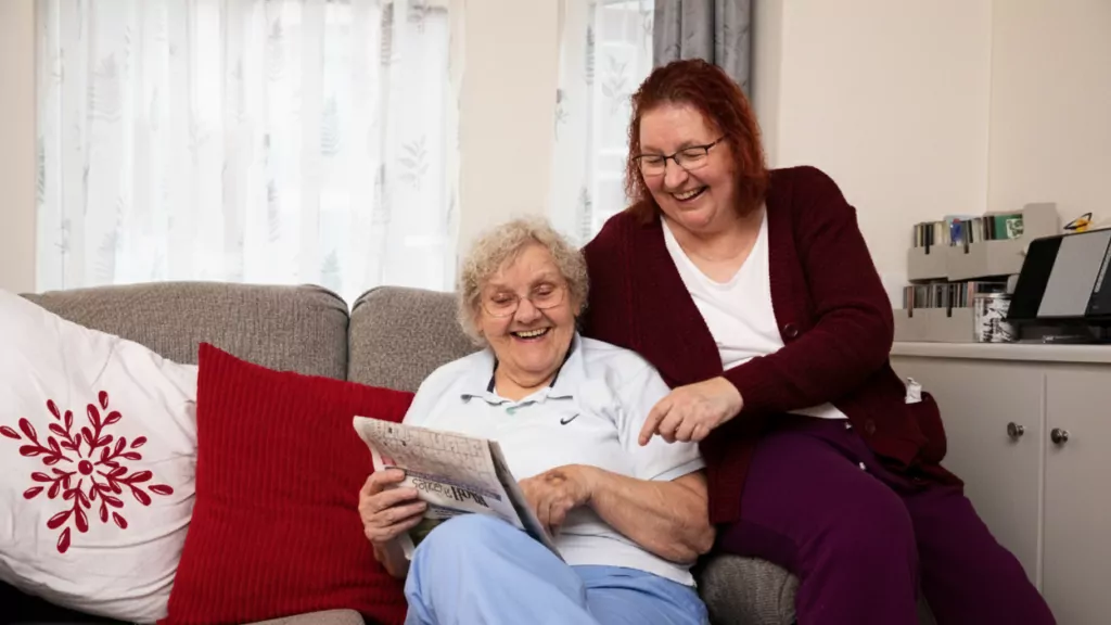 Two woman reading and laughing on a couch